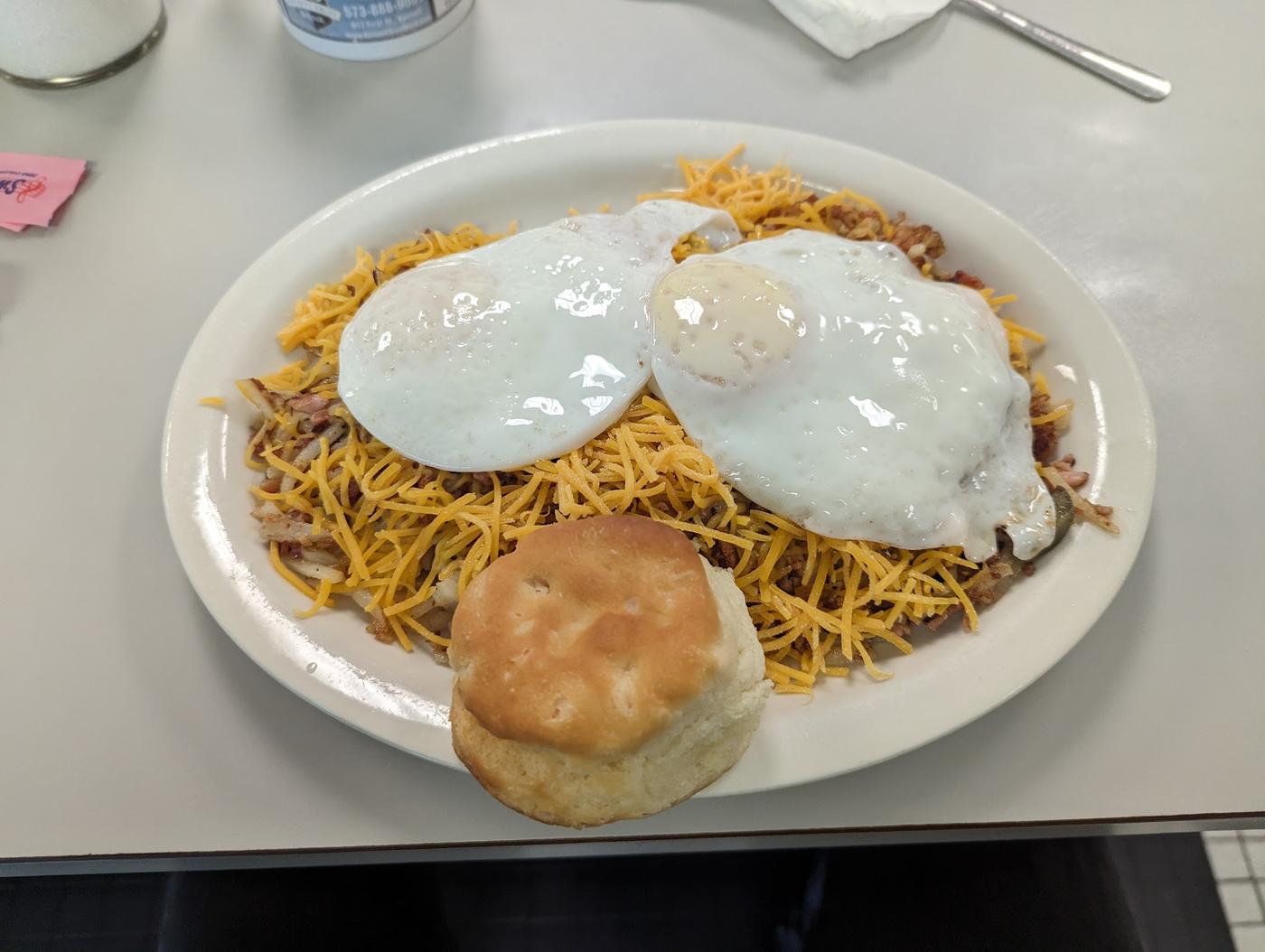 Two eggs over hash browns with shredded cheddar and a biscuit