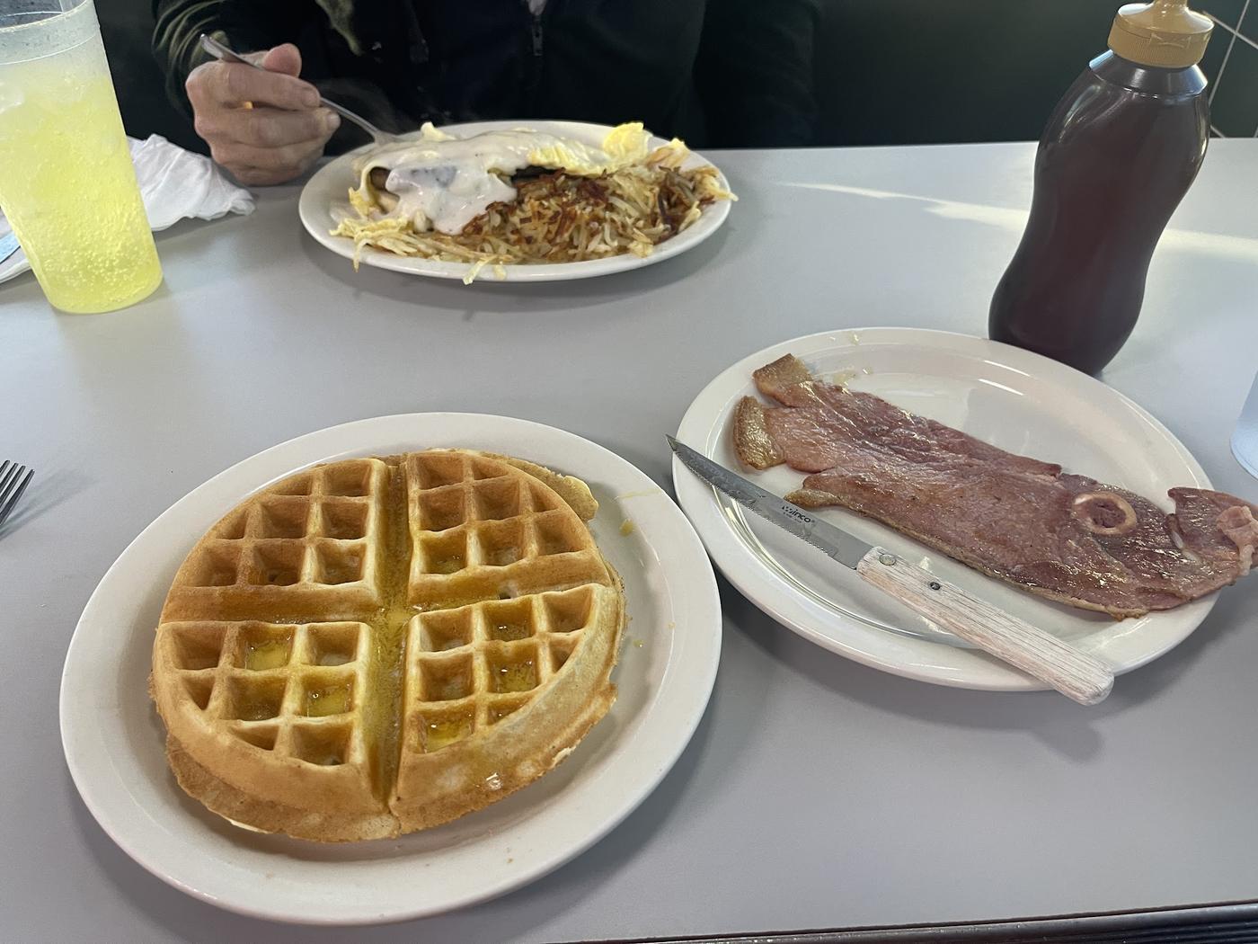 A Belgian waffle beside a thick slab of fried bologna